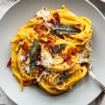 Bowl of butternut squash spaghetti carbonara with bacon and sage leaves.