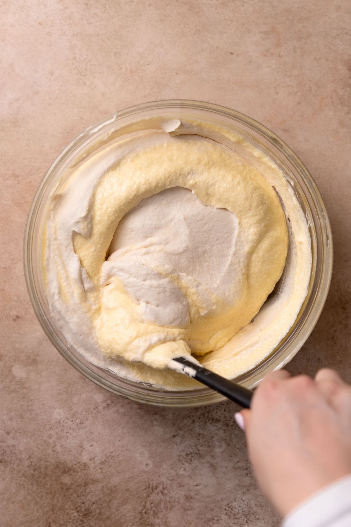 Folding whipped cream into the mascarpone mixture.
