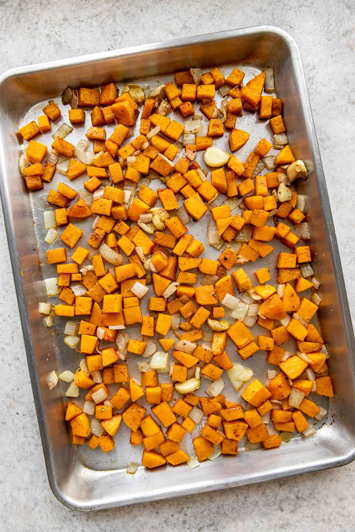 Roasted butternut squash and onion on a baking sheet.