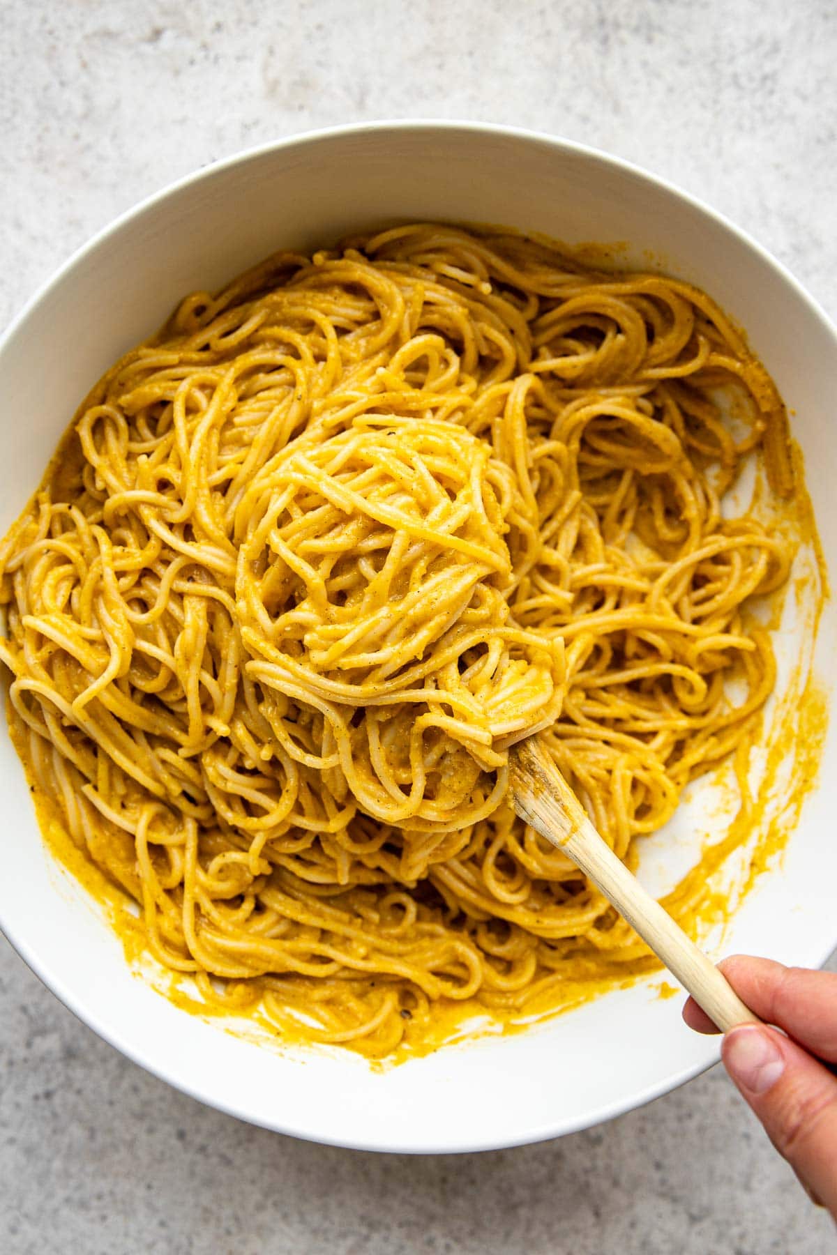Stirring pasta with butternut squash carbobara sauce.