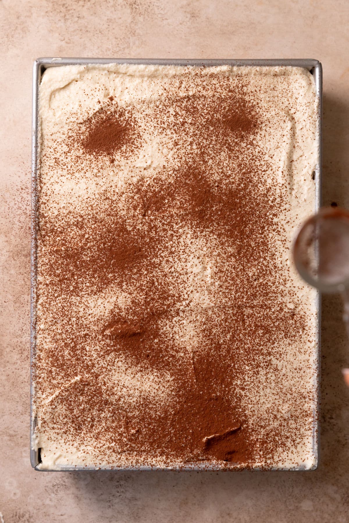 Topping Italian tiramisu with cocoa powder.