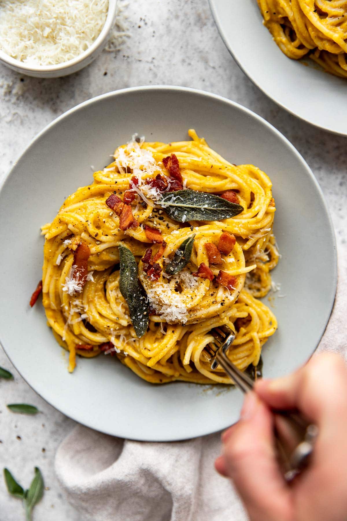 Twirling butternut squash spaghetti carbonara pasta onto a fork.