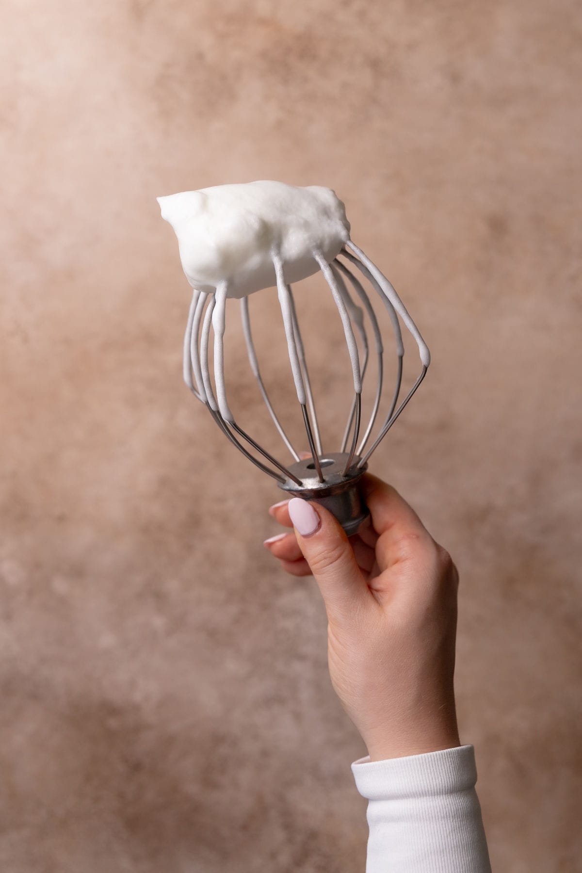 Whipped egg whites on a stand mixer beater.