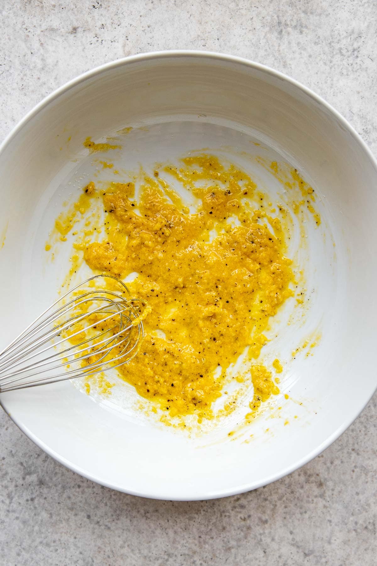 Whisked egg yolks, parmesan cheese, and black pepper in a bowl.