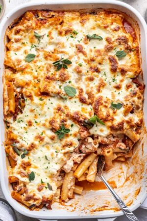 Cheesy baked ziti with sausage and ricotta cheese in a casserole dish.