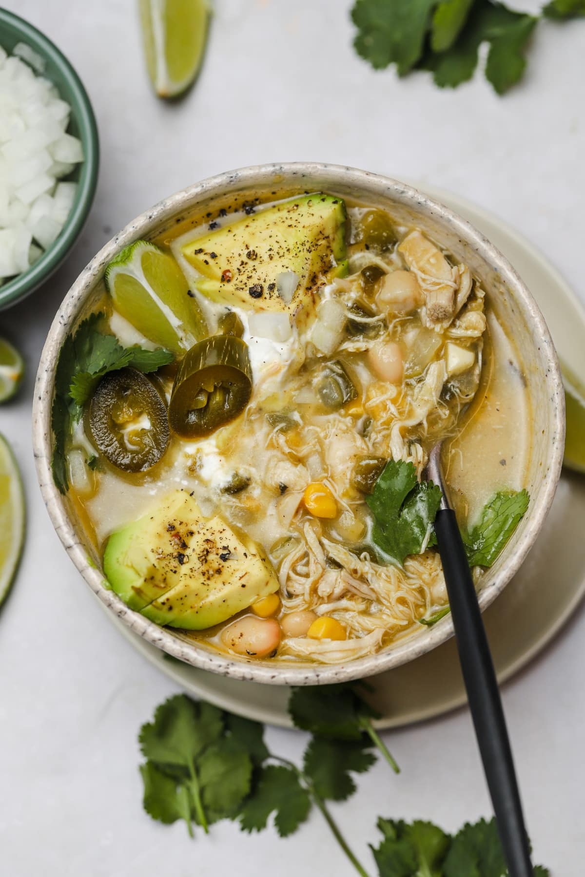 Green chicken chili soup with avocado in a bowl.