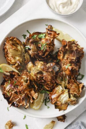 Jewish fried artichokes in a bowl with chopped parsley.