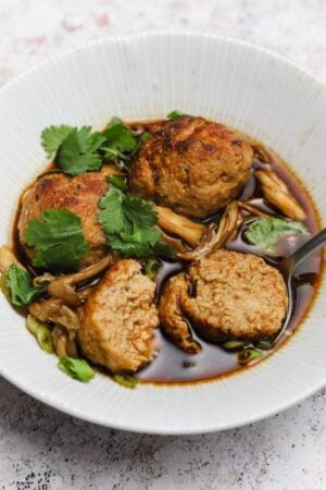 Pork meatballs with Chinese chili oil and mushrooms in a bowl with broth.