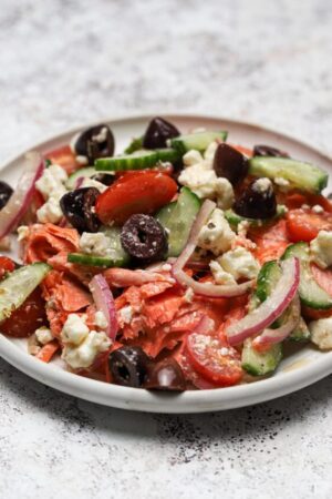 Wild Alaskan salmon on a plate with Greek salad.