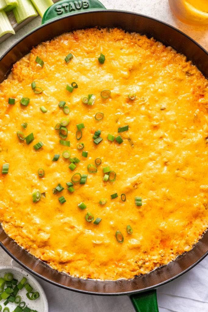 Cheesy baked buffalo chicken dip in a cast iron skillet.