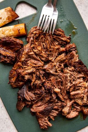 Shredded braised beef birria on a cutting board.