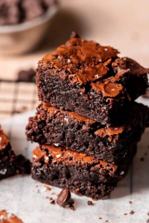 Stacked chocolate brownies on parchment.