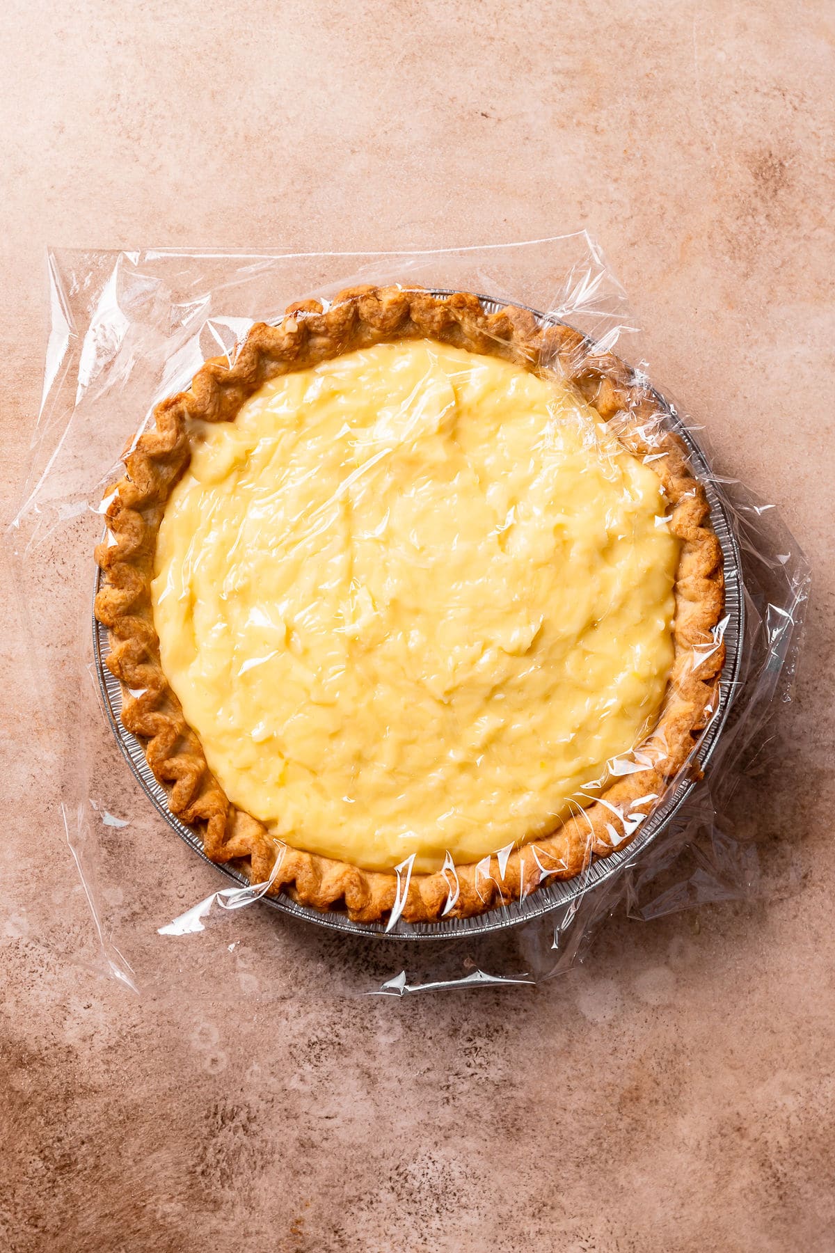 Coconut custard in a pie shell with plastic wrap pressed on top.