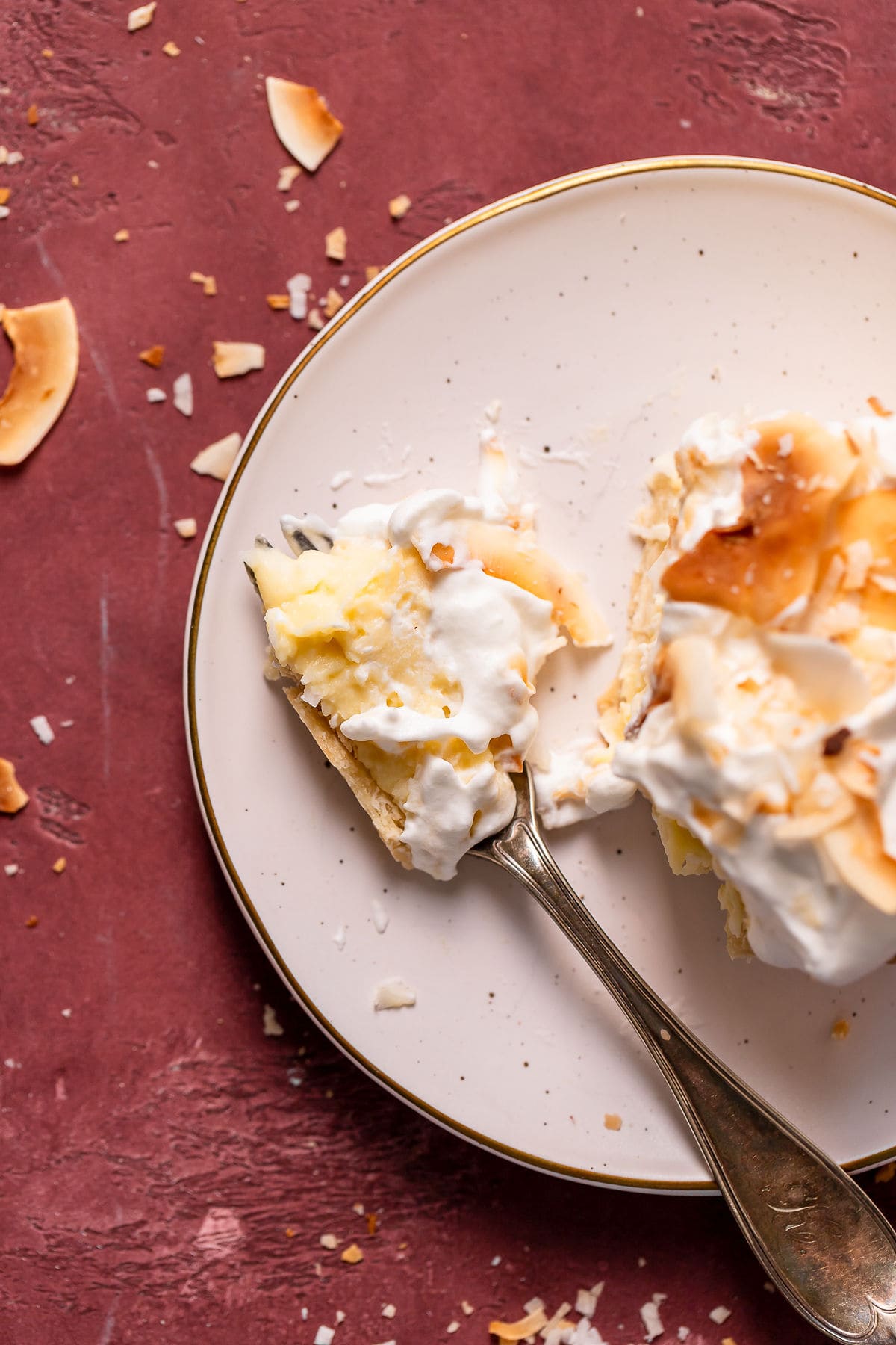 Slice of coconut cream pie on a plate with a fork.