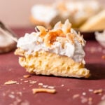 Slice of coconut cream pie with toasted coconut flakes.