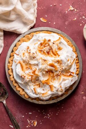 Homemade coconut cream pie with whipped cream and coconut flakes.