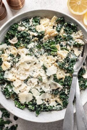Kale Caesar pasta salad in a bowl with extra shaved parmesan.
