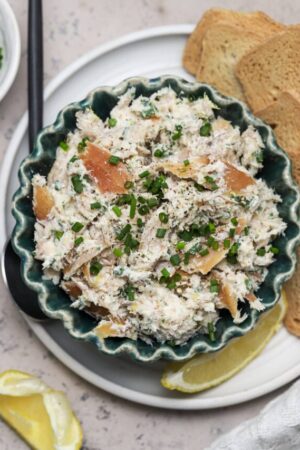 Smoked trout dip in a small bowl with crackers on a plate.