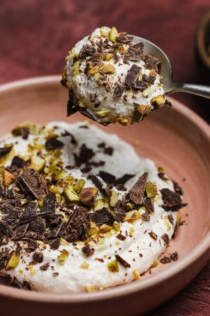 Spoonful of whipped ricotta cream with chocolate and pistachios.