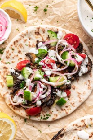 Mushroom shawarma on pita bread with veggies and white sauce.