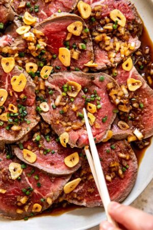 Picking up a slice of tataki of beef with chopsticks.